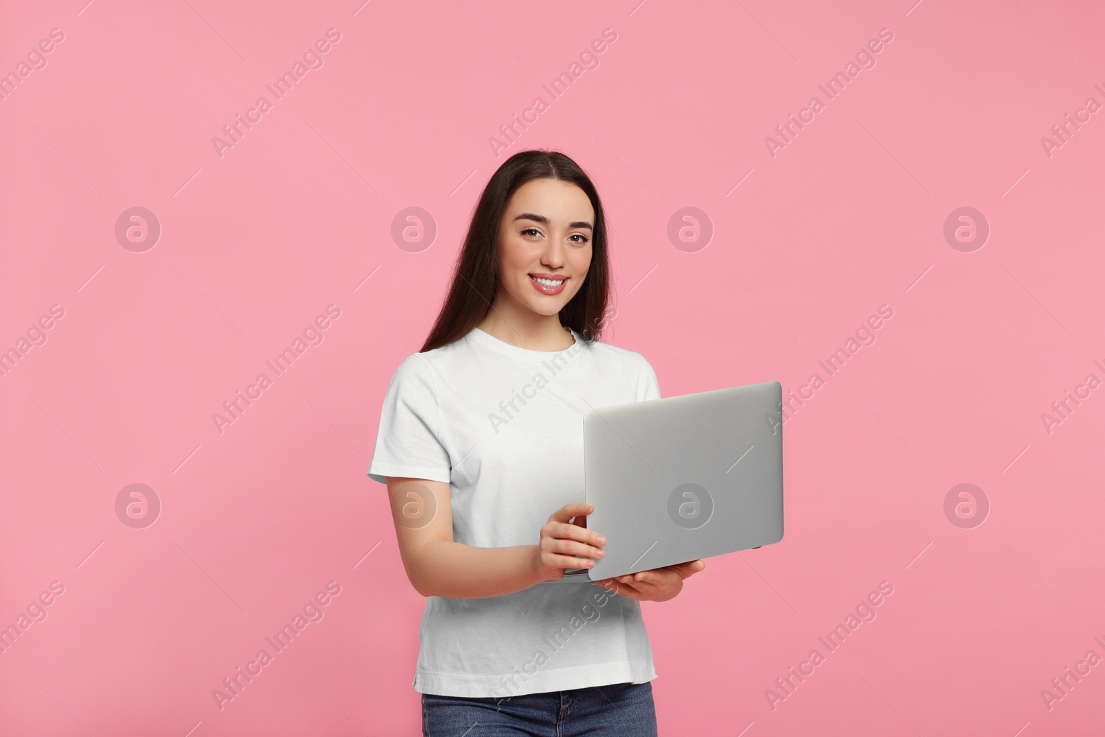 Photo of Smiling young woman with laptop on pink background