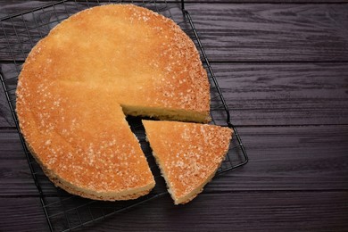 Photo of Tasty sponge cake on wooden table, top view. Space for text