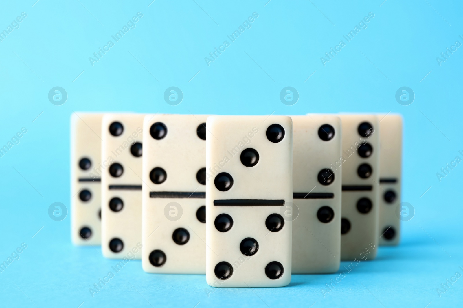 Photo of White domino tiles on turquoise background, closeup