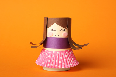 Photo of Toy doll made of toilet paper hub on orange background