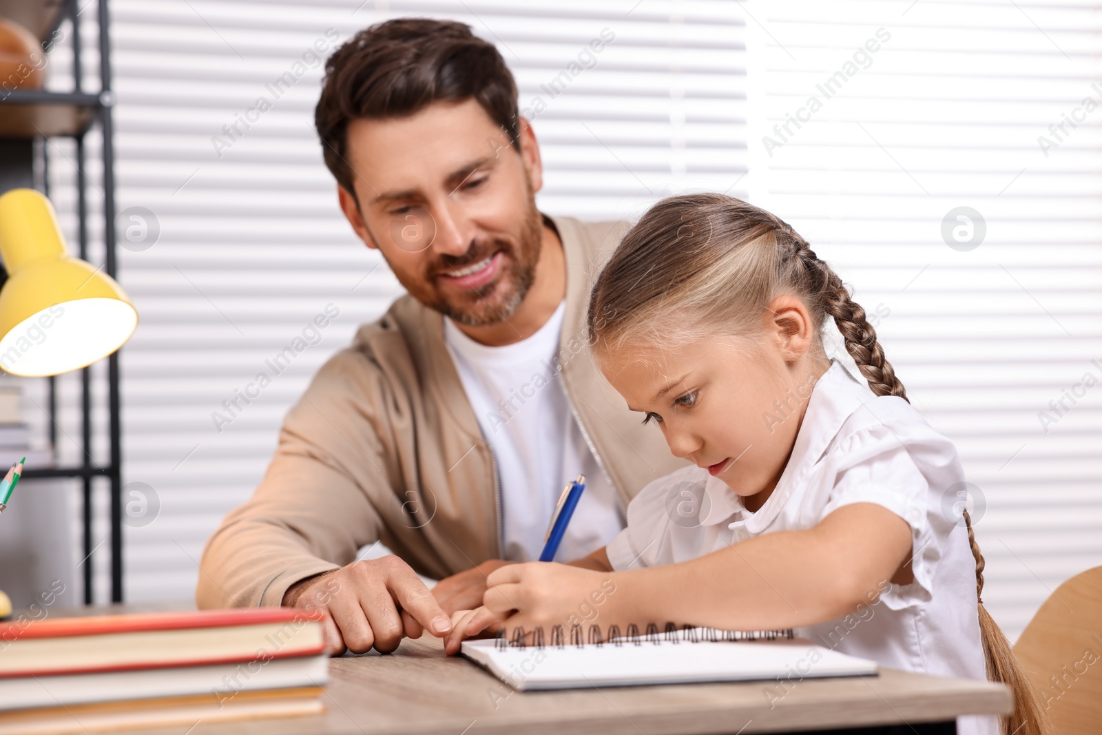 Photo of Dyslexia problem. Father helping daughter with homework at table indoors, selective focus