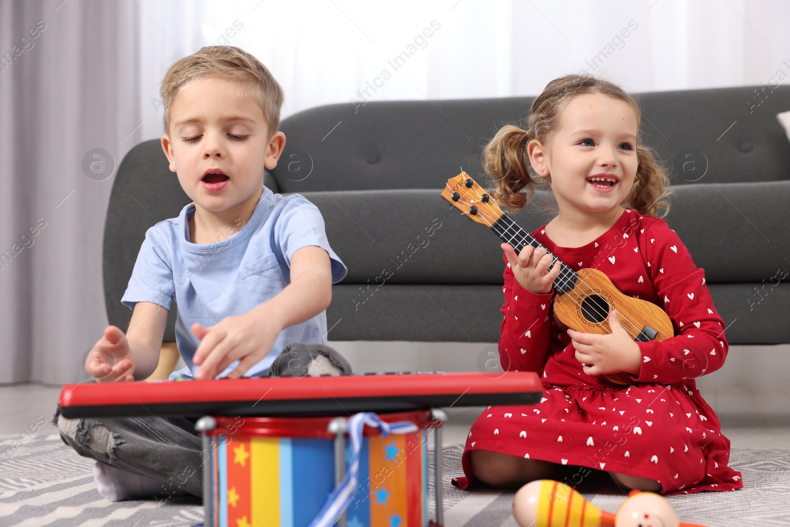 Photo of Little children playing toy musical instruments at home