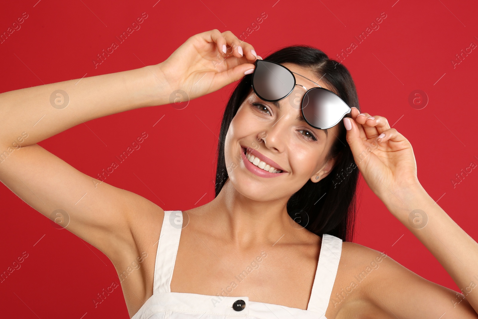 Photo of Beautiful woman wearing sunglasses on red background