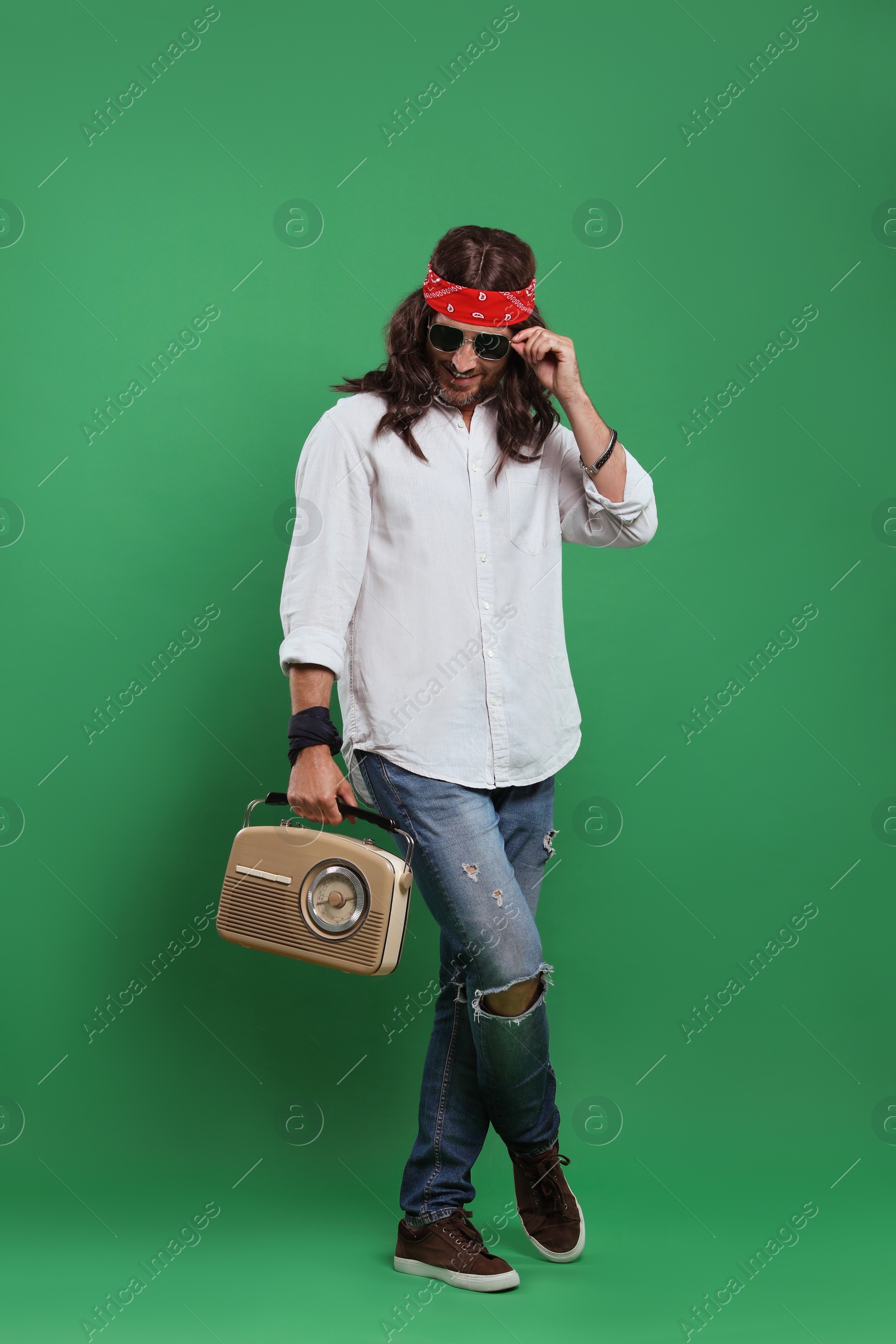 Photo of Stylish hippie man in sunglasses with retro radio receiver on green background