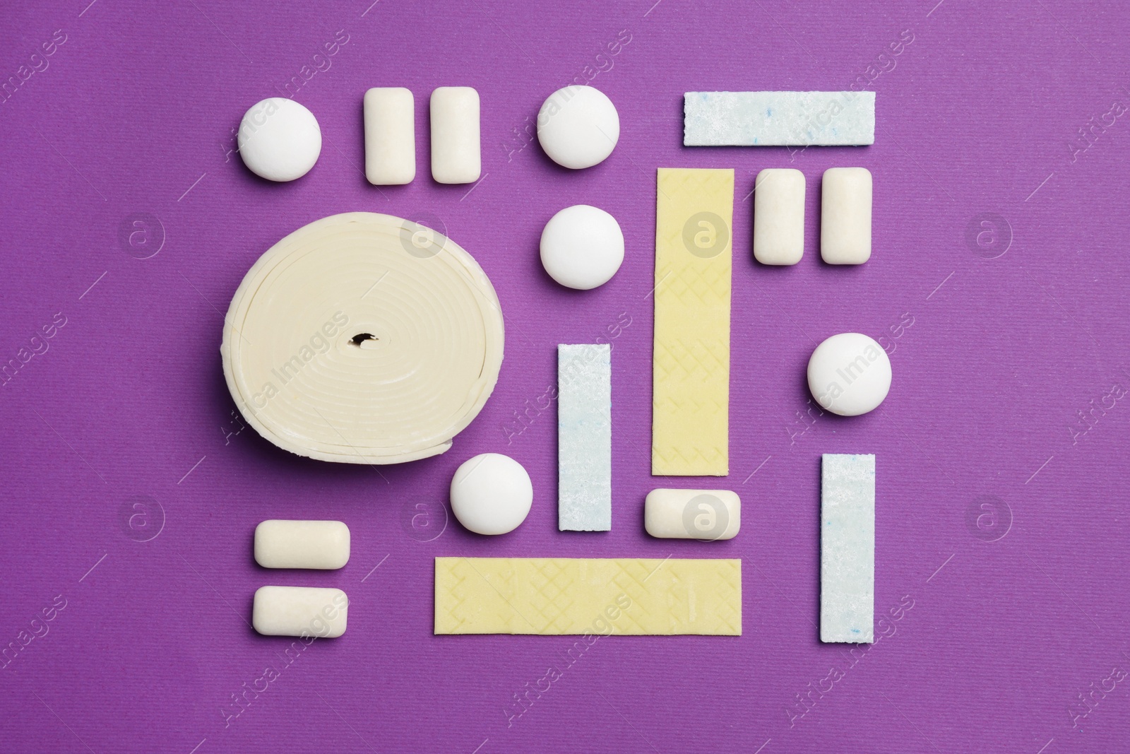 Photo of Different tasty colorful bubble gums on purple background, flat lay
