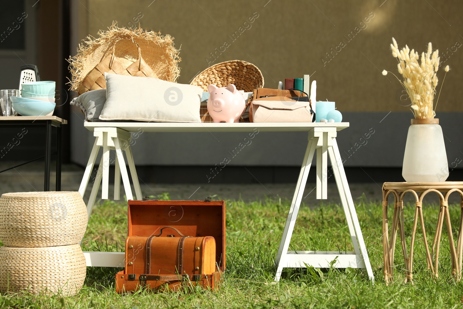 Photo of Many different items on white table in yard. Garage sale