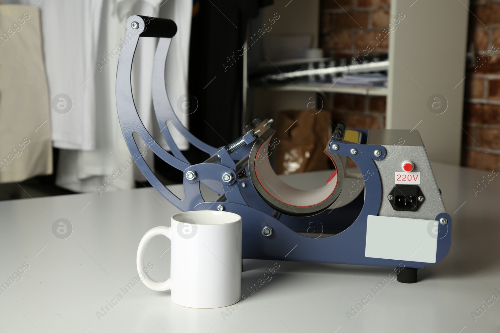 Photo of Printing logo. Heat press and cup on white table, space for text