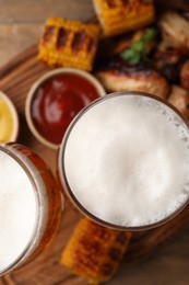 Photo of Glasses with beer, delicious baked chicken wings and grilled corn on table, flat lay