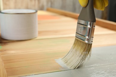 Photo of Worker applying white paint onto wooden surface, closeup. Space for text