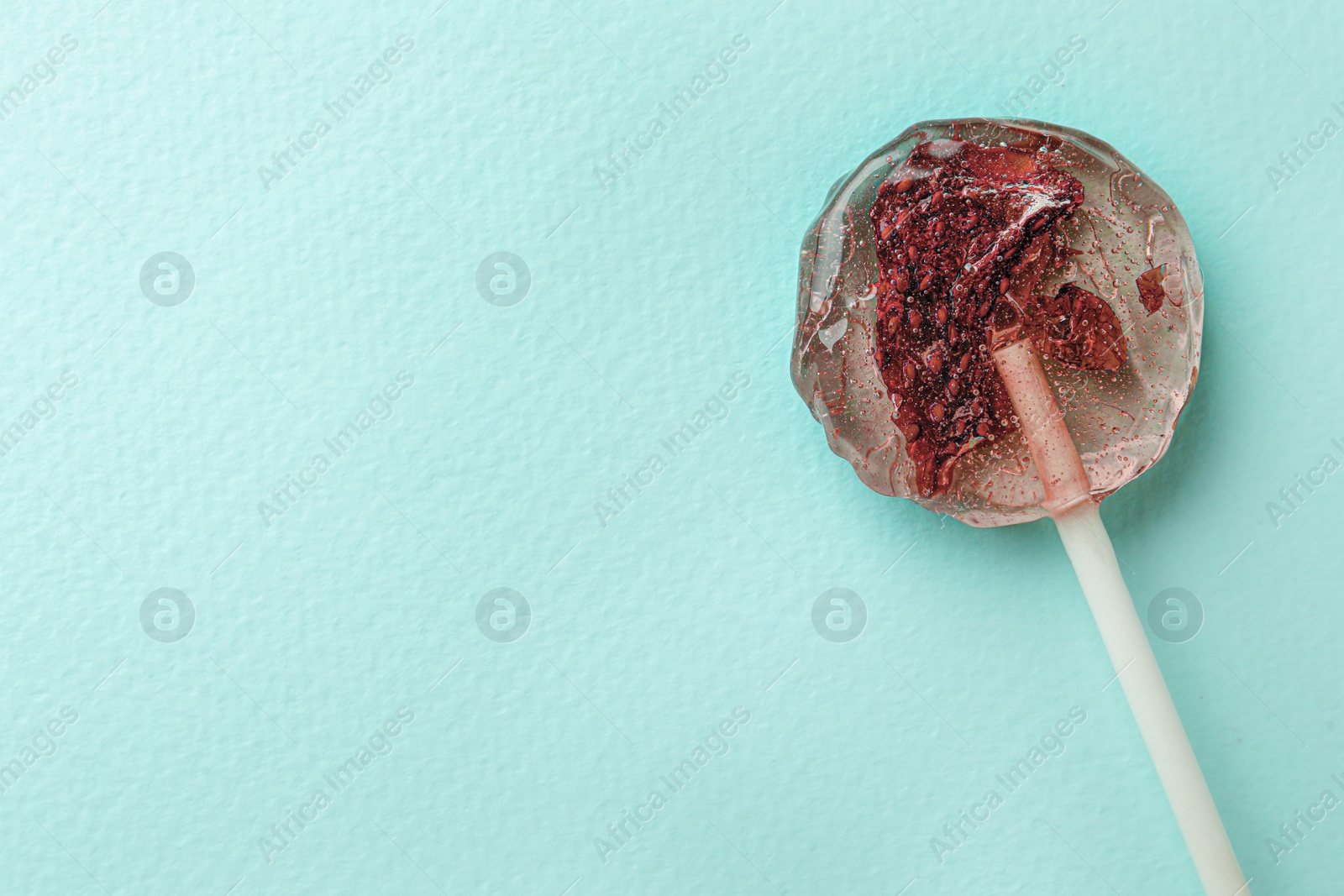 Photo of Sweet colorful lollipop with berries on turquoise background, top view. Space for text