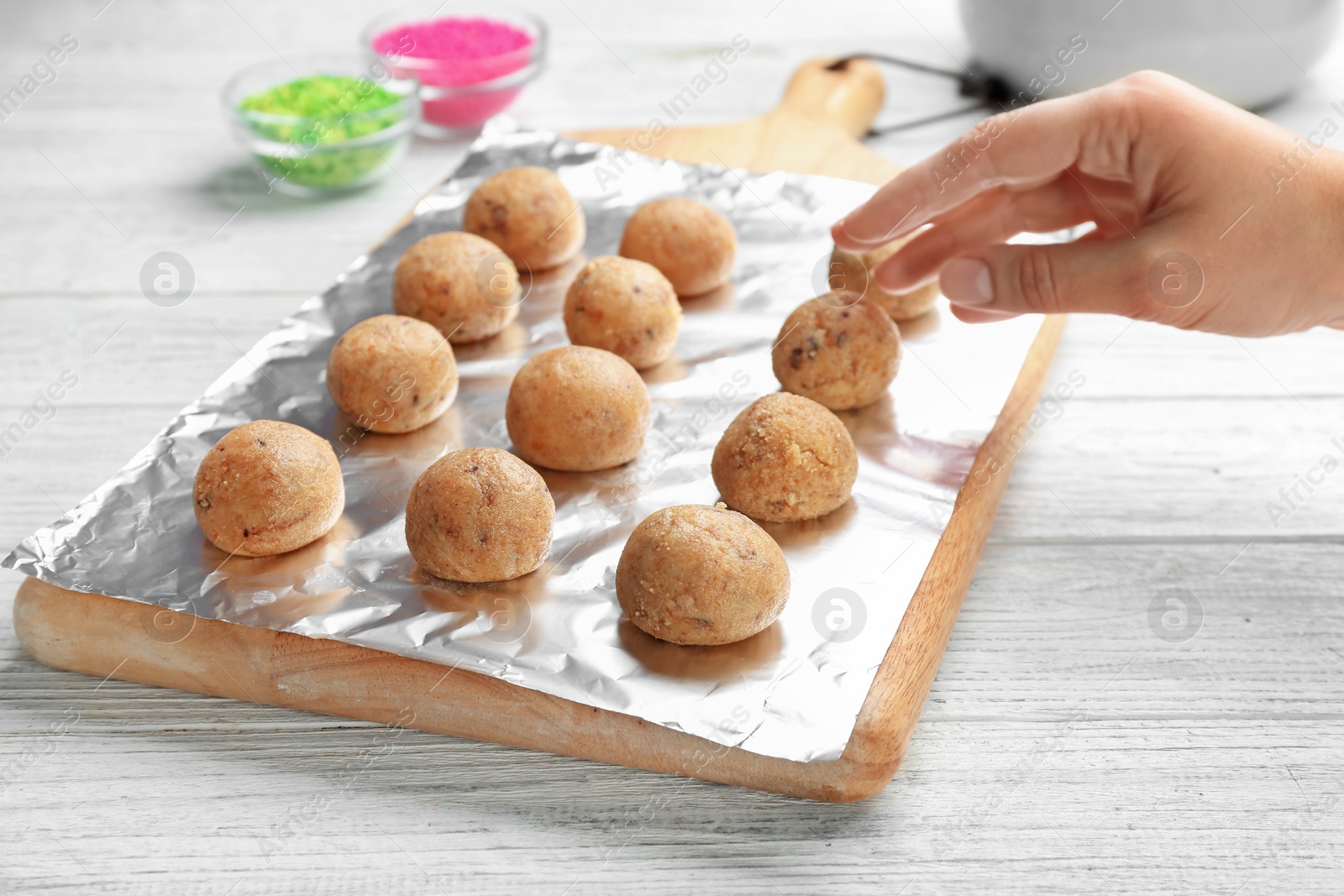 Photo of Woman with half made cake pops at white wooden table, closeup. Home cooking