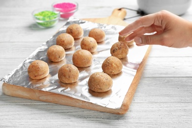 Woman with half made cake pops at white wooden table, closeup. Home cooking