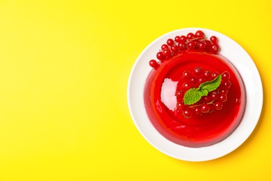 Photo of Delicious fresh red jelly with berries and mint on yellow background, top view. Space for text