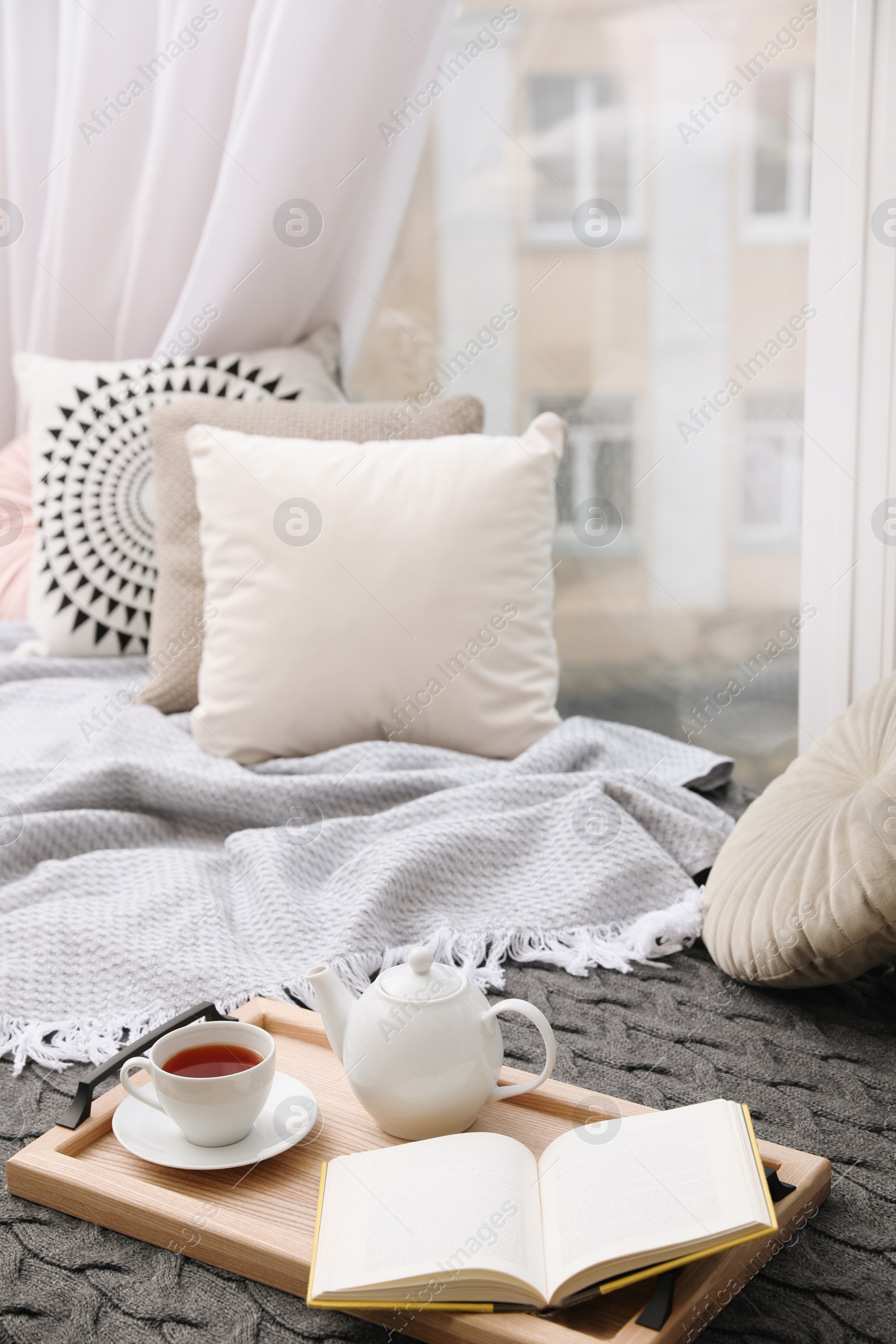 Photo of Comfortable lounge area with blanket and soft pillows near window in room