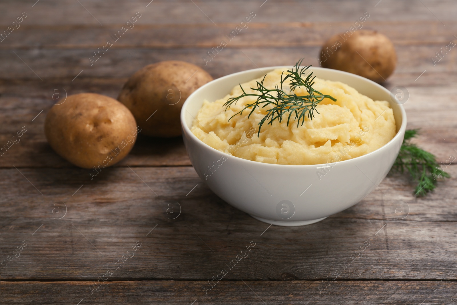 Photo of Bowl with mashed potatoes on wooden table. Space for text