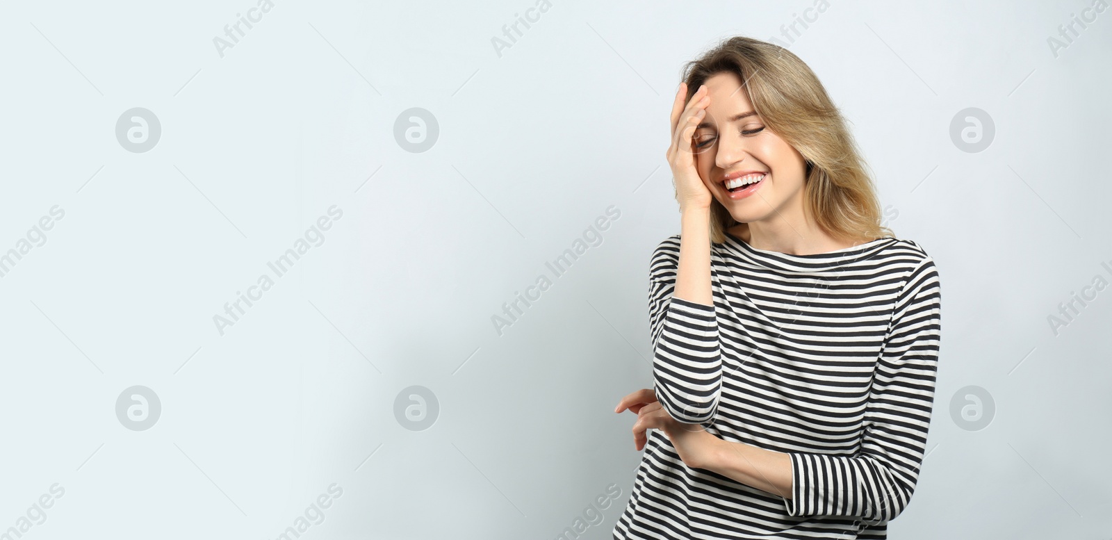 Photo of Portrait of happy young woman with beautiful blonde hair and charming smile on light background