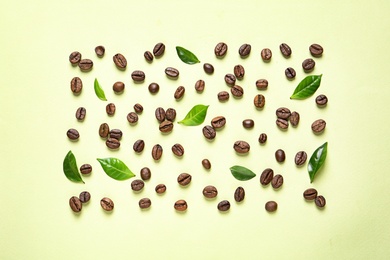 Photo of Fresh green coffee leaves and beans on light green background, flat lay