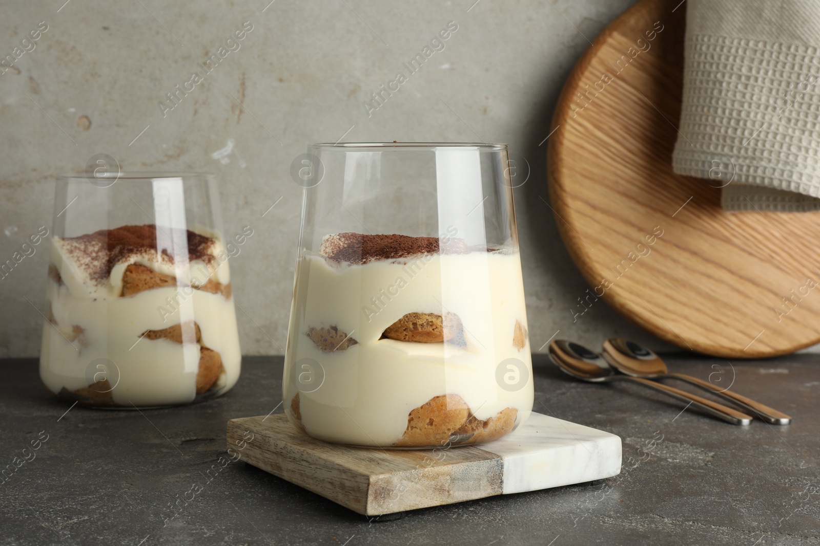 Photo of Delicious tiramisu in glasses on grey table