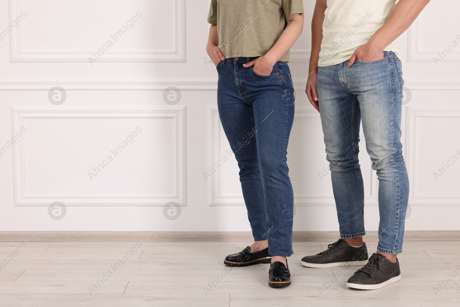 Photo of People in stylish jeans near white wall indoors, closeup. Space for text