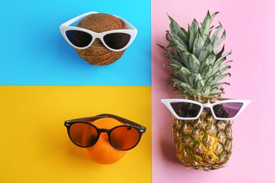 Funny faces made of tropical fruits and sunglasses on color background, flat lay. Vacation time