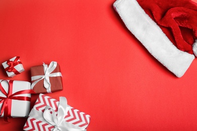 Santa Claus red hat and gift boxes on color background, top view