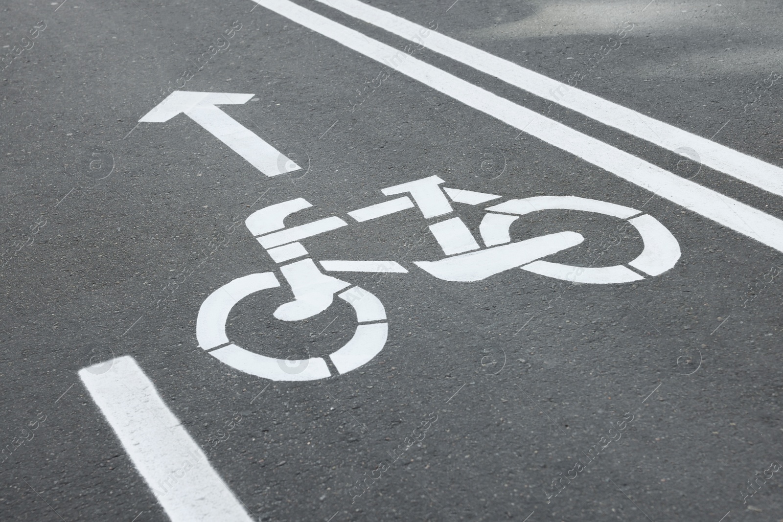 Photo of Bicycle lane with sign and arrow pointing direction on asphalt, closeup