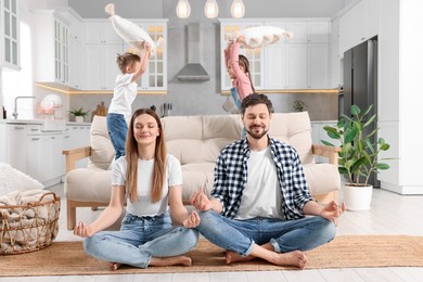 Photo of Parents meditating while their children playing with cushions at home