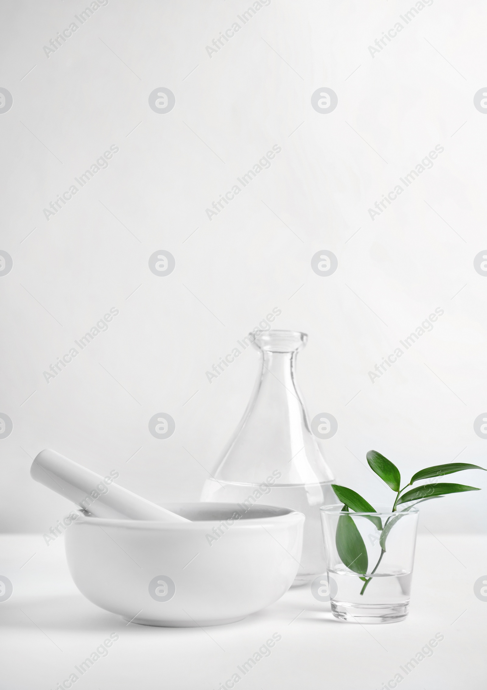 Photo of Composition with mortar and pestle on table against light background. Homemade cosmetic products