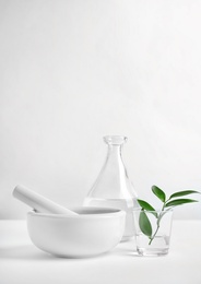 Photo of Composition with mortar and pestle on table against light background. Homemade cosmetic products