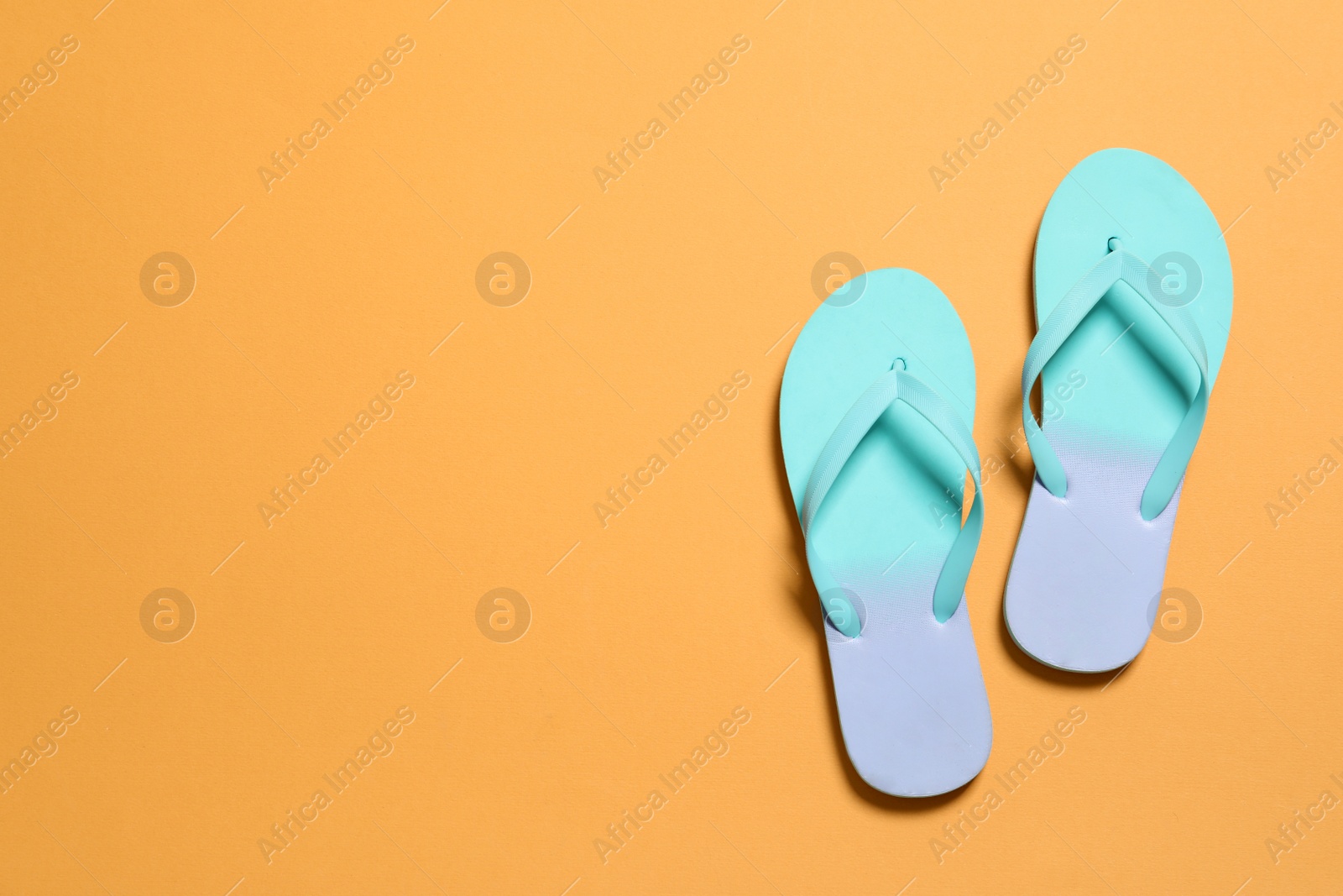 Photo of Bright flip flops on color background, top view with space for text. Beach accessories