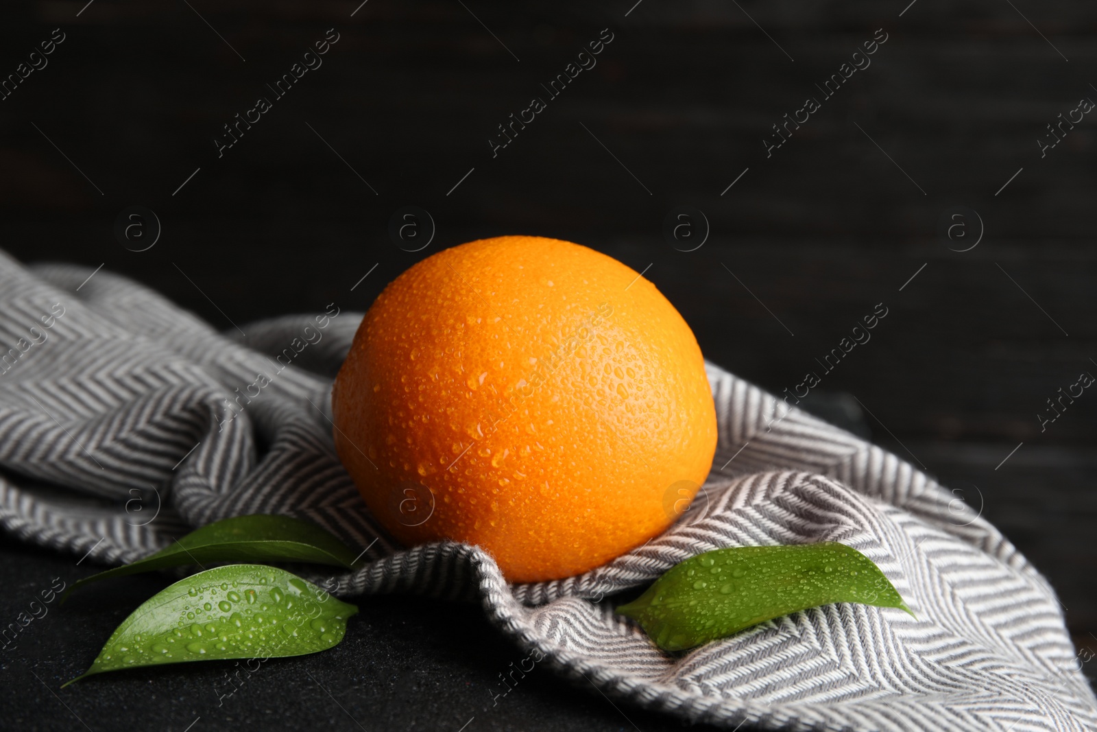 Photo of Fresh orange with leaves and napkin on table