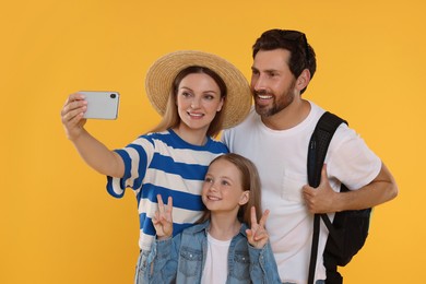 Happy family taking selfie on orange background