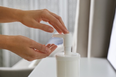 Photo of Woman applying hand sanitizer indoors, closeup. Personal hygiene during COVID-19 pandemic