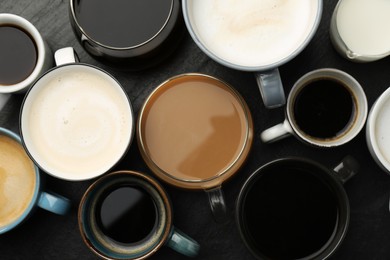 Different coffee drinks in cups on dark textured table, flat lay