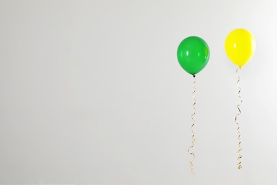 Photo of Different bright balloons on light background, space for text. Celebration time