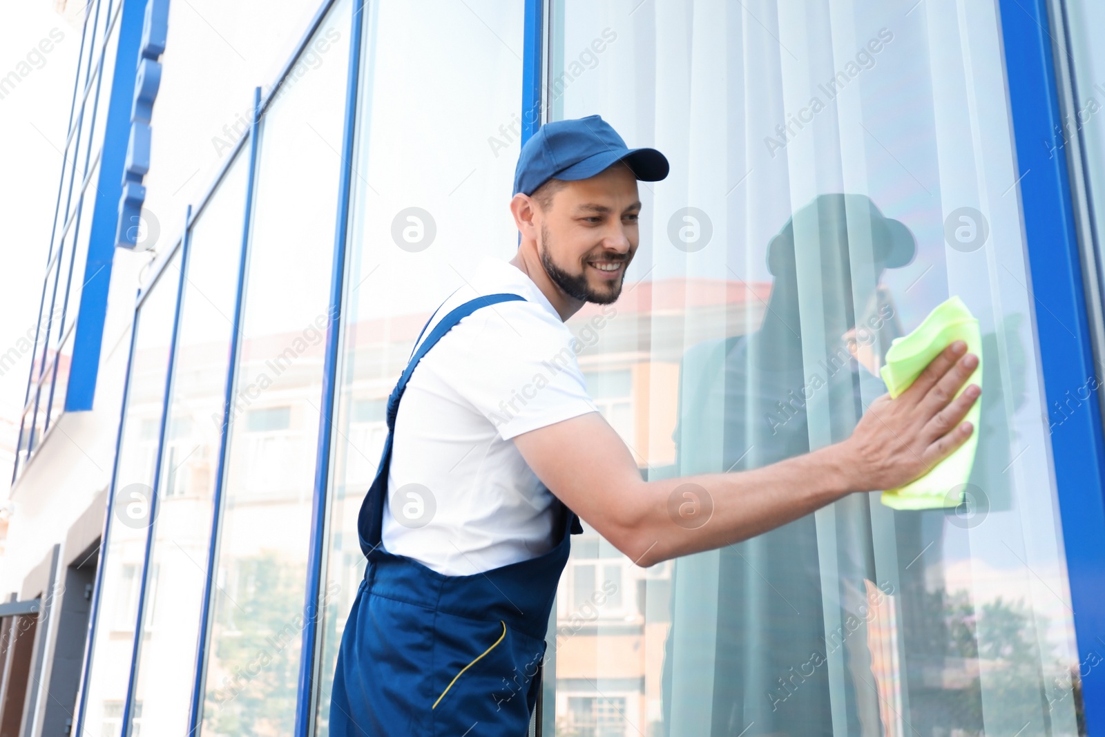 Photo of Male worker washing window glass from outside