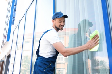 Male worker washing window glass from outside