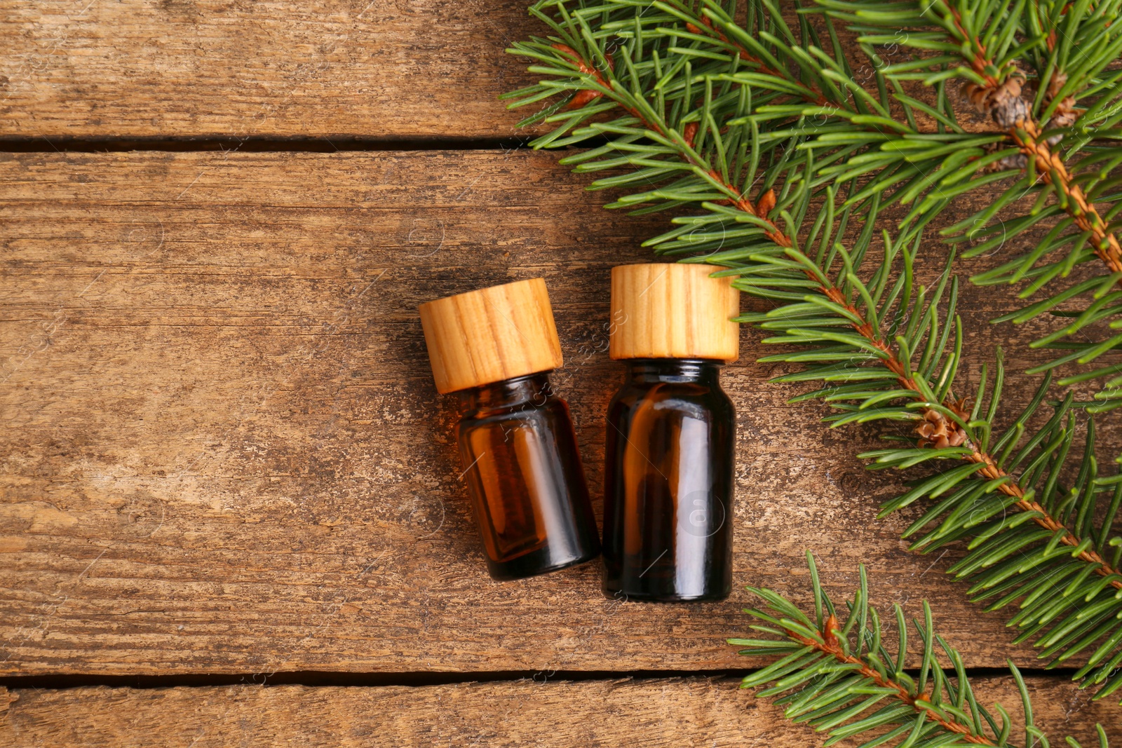 Bottles of pine essential oil and conifer tree branches on wooden table, flat lay. Space for text Photo of Bottles of pine essential oil and conifer tree branches on wooden table, flat lay. Space for text