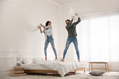 Happy young couple having fun pillow fight in bedroom