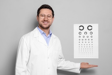 Ophthalmologist showing vision test chart on gray wall