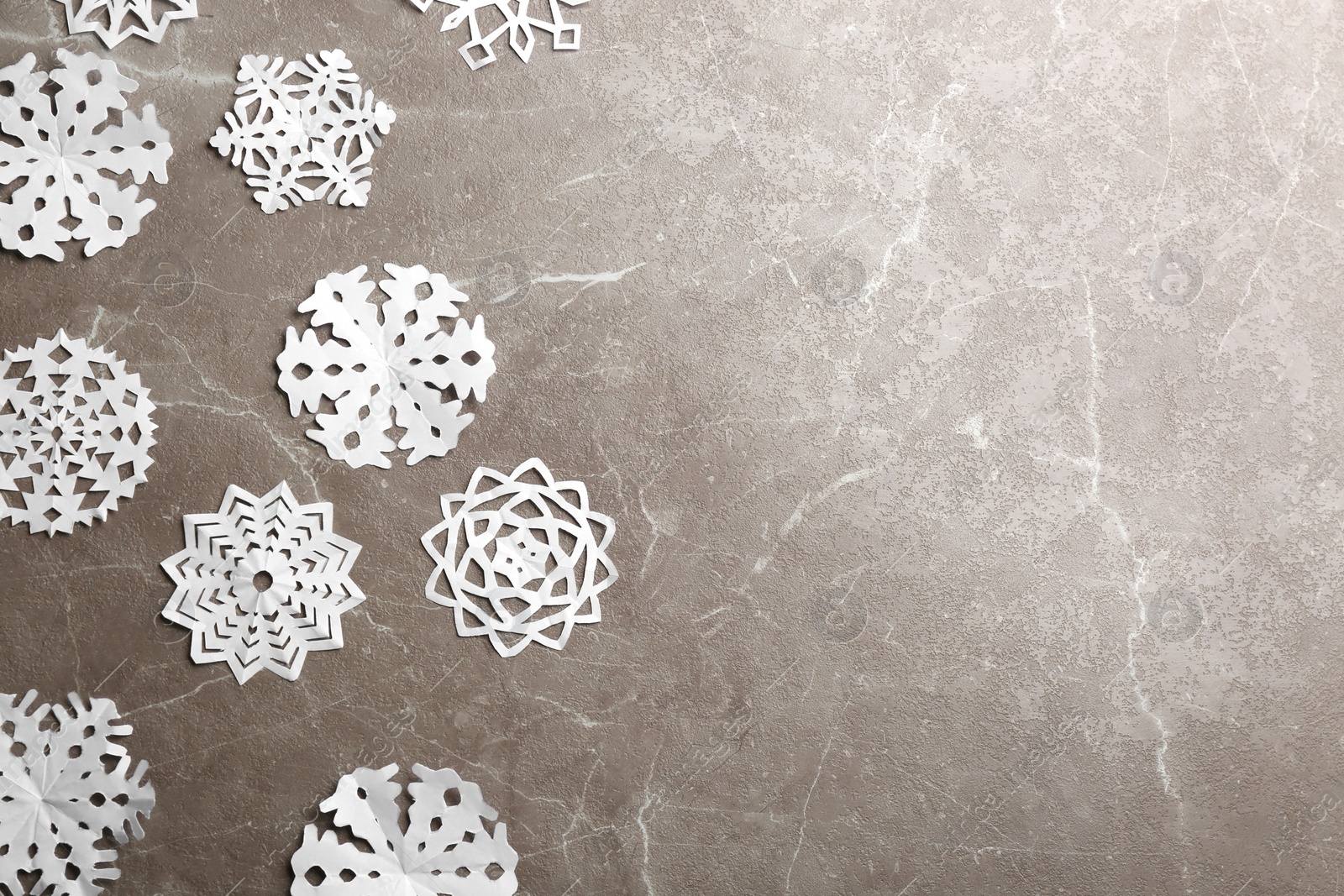 Photo of Many paper snowflakes on grey background, flat lay. Space for text