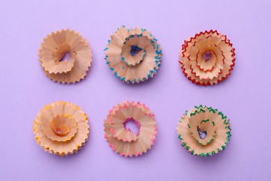 Photo of Colorful wooden pencil shavings on violet background, flat lay