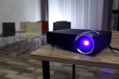 Photo of Modern video projector on wooden table in conference room