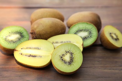 Photo of Many whole and cut fresh kiwis on wooden table