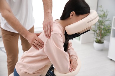 Woman receiving massage in modern chair indoors