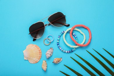 Flat lay composition with stylish sunglasses, seashells and accessories on light blue background