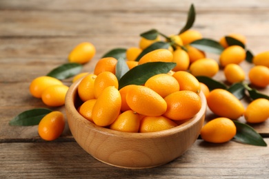 Fresh ripe kumquats in bowl on wooden table