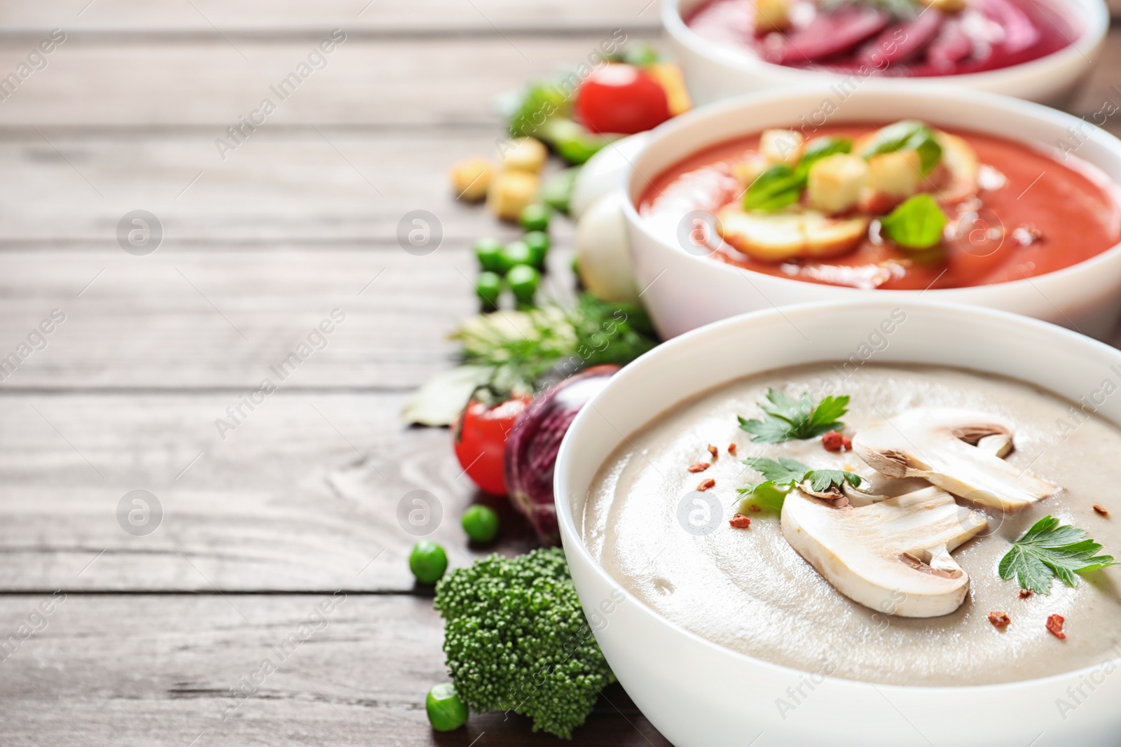 Photo of Various cream soups, ingredients on wooden background, space for text. Healthy food