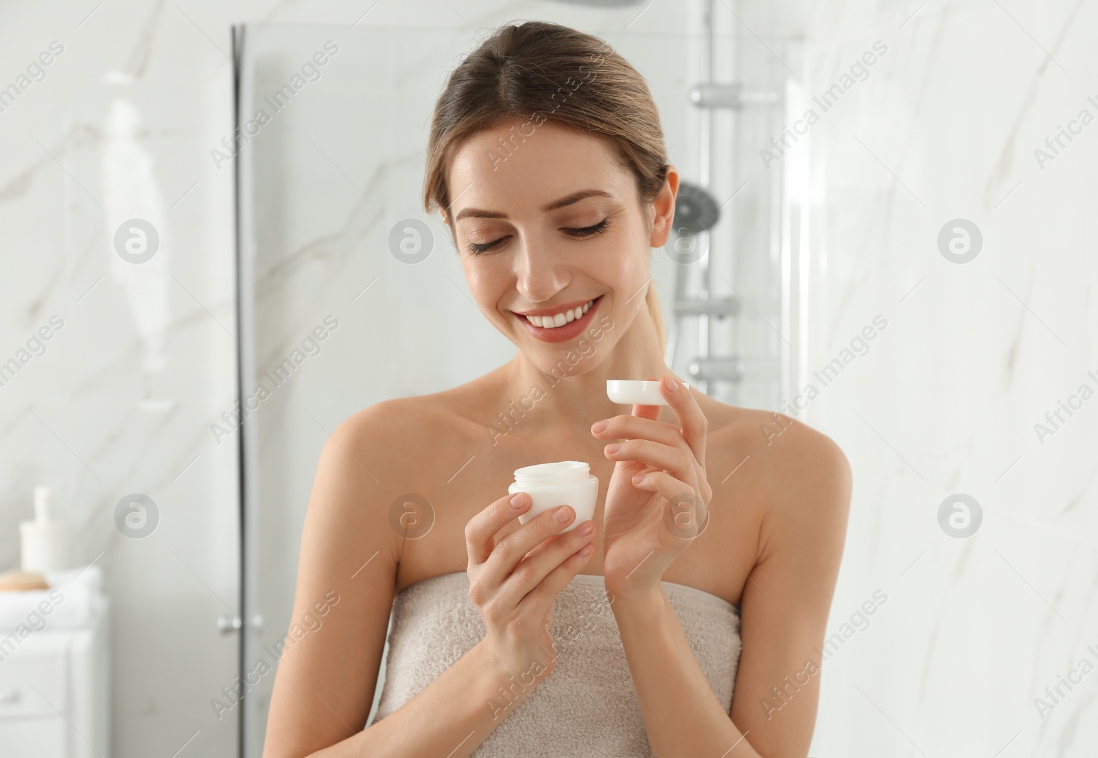 Photo of Young woman with face cream in bathroom