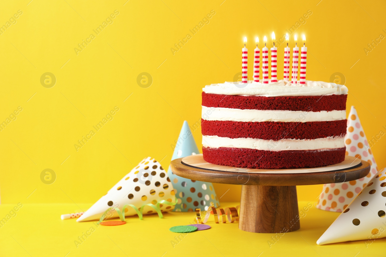 Photo of Delicious homemade red velvet cake with candles on yellow background. Space for text